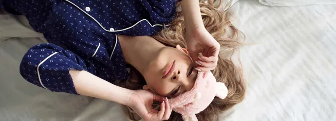 Dívka s oční maskou na posteli má v noci ucpaný nos