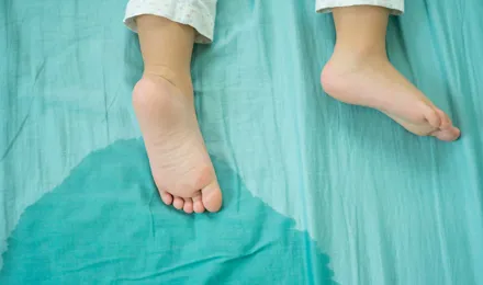 Κοντινό πλάνο στα πόδια ενός παιδιού και ούρα σε ένα στρώμα