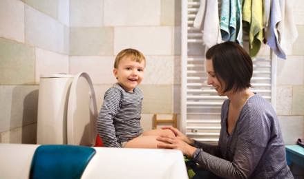 Μια μητέρα βοηθά τον γιο της να καθίσει στη λεκάνη της τουαλέτας