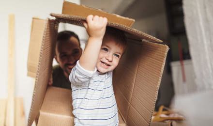 Ein kleiner Junge trägt eine Kiste während eines Umzugs aus einem Haus