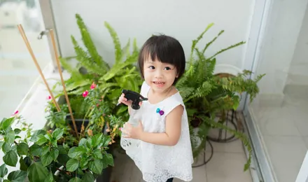 Маленькая девочка ухаживает за комнатными растениями