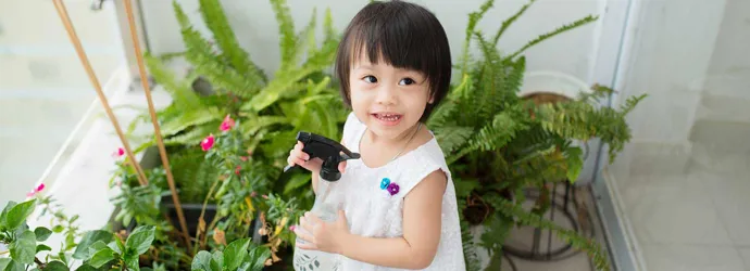 Маленькая девочка ухаживает за комнатными растениями