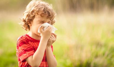 Мальчик с пыльцевой аллергией сморкается снаружи в поле