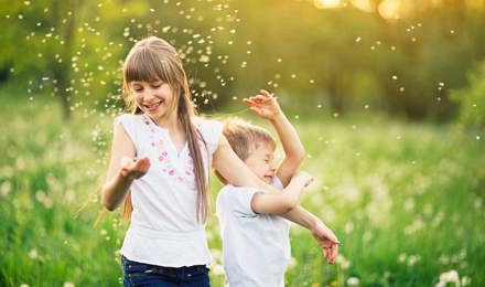 Fiú- és lánytestvér játszik a pitypangmezőn pollennel körülvéve
