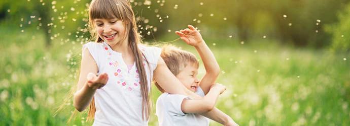 Fiú- és lánytestvér játszik a pitypangmezőn pollennel körülvéve