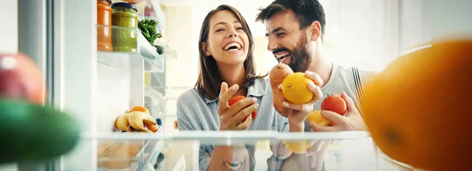 Un cuplu luând niște fructe și legume din frigider