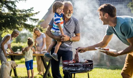 Muž připravuje barbecue na dvorku rodinného domu