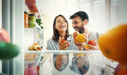Пара выбирает некоторые фрукты и овощи из холодильника