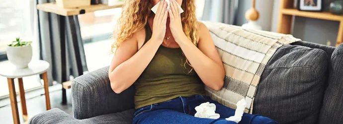 Žena sa simptomima prehlade i alergije puše nos