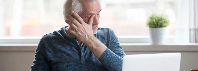 Ένας ώριμος άντρας μπροστά στο λάπτοπ με φαγούρα στο μάτι