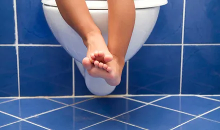 Τα πόδια ενός παιδιού που κρέμονται από τη λεκάνη της τουαλέτας