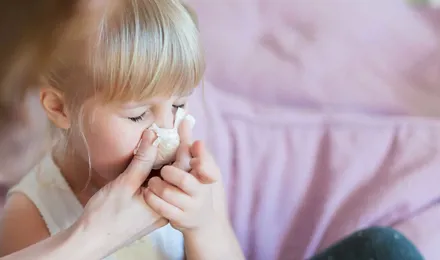 Egy anya segít lányának fújni az orrát papír zsebkendővel