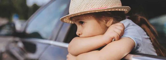 Copil cu greață în mașină purtând o pălărie în timp ce