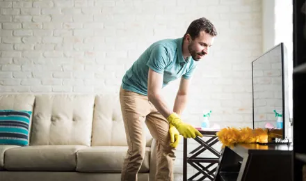 Человек потирает от пыли свой дом с тряпкой