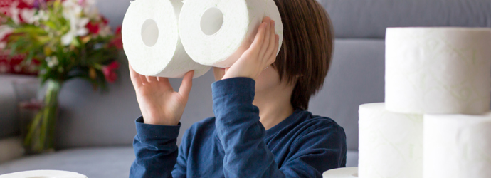 Egy gyermek toalettpapír-gurigákkal játszik
