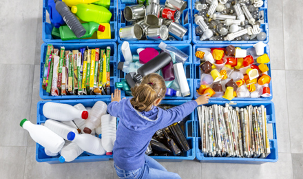 Egy gyermek válogat az újrahasznosításhoz otthon
