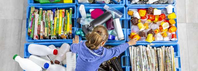 Egy gyermek válogat az újrahasznosításhoz otthon
